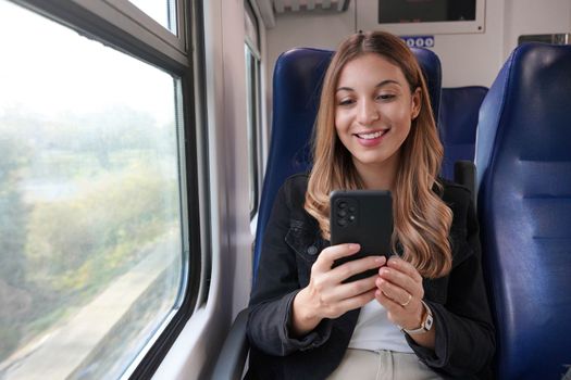 Smiling business woman using public transport, sitting with cellphone on train