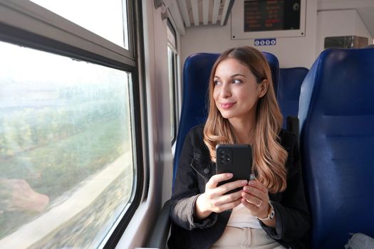 Beautiful woman traveling with train holding smartphone sitting and relaxed 