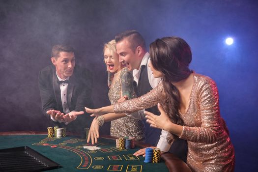 Group of a stylish rich friends are playing poker at casino.