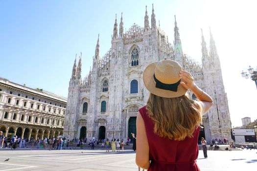 Holidays in Italy. Rear view of traveler girl holds hat in Milan Cathedral Square, Italy.