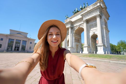 Beautiful smiling traveler girl takes self portrait in Milan, Italy