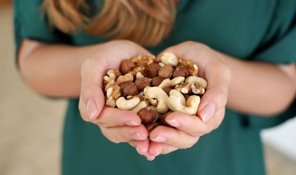 Woman showing abundance and variety of nuts mix of dried fruits in her hands