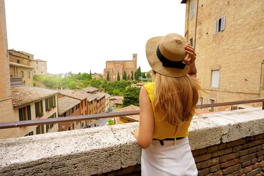 Holidays in Tuscany. Back view of beautiful stylish tourist girl in Siena historic town of Tuscany, Italy.