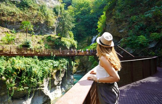 Young woman walking on the path into the wild enjoying landscape with waterfalls and the gorges of a natural canyon