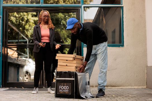 Pizzeria delivery service, courier passing woman pizza boxes stack