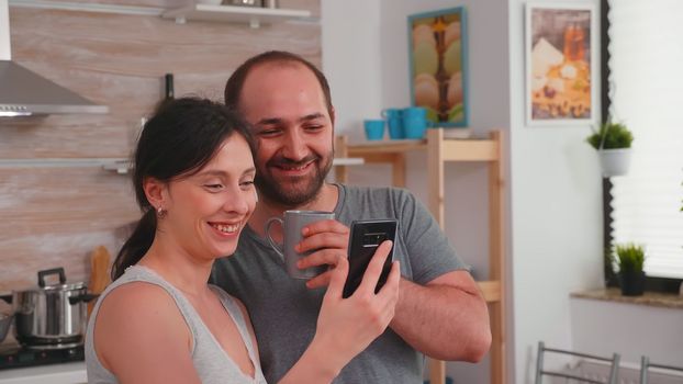 Authentic couple in the morning smiling and looking at phone