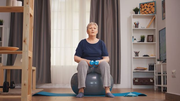Old retired woman lifting dumbbells