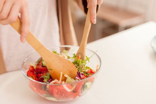 Hands mixing salad ingredients
