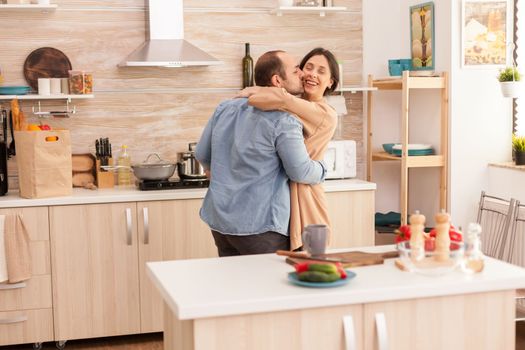 Man kissing wife in kitchen