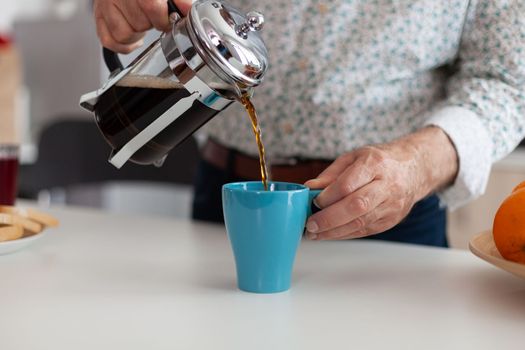 Man's hand pouring aromatic coffee into a blue cup