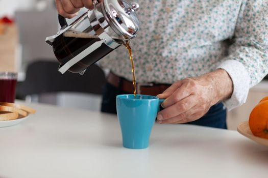 Senior man using french press and pouring hot drink