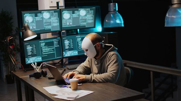 Cyber impostor wearing mask hacking database servers