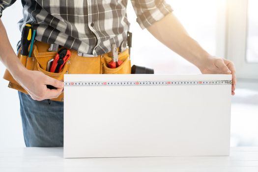 Worker measuring furniture board with tape