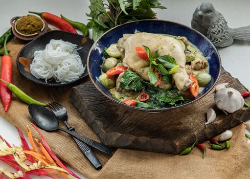 Green curry with Chicken and Thai eggplants (Kaeng khiao wan) in Ceramic bowl served with Rice noodles.