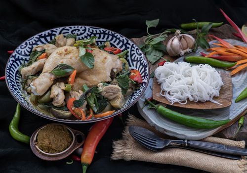 Green curry with Chicken and Thai eggplants (Kaeng khiao wan) in Ceramic bowl served with Rice noodles.