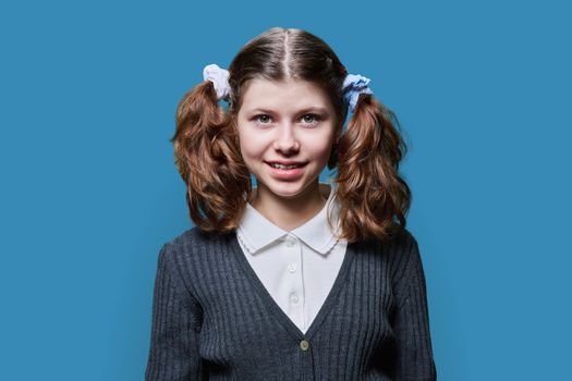 Portrait of smiling child schoolgirl on blue studio background
