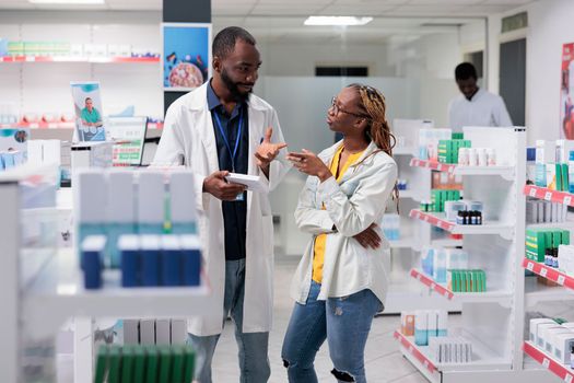 African american pharmacist and buyer discussing medicaments in drugstore