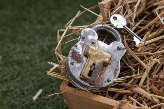 Old vintage iron padlock and key on straw background in wooden box. 