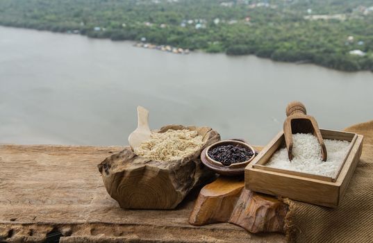 Various types of rice : Brown rice, Jasmine rice and Riceberry on old wooden table with natural scenery. Organic raw rice collection, Healthy food and diet concept, Selective focus.