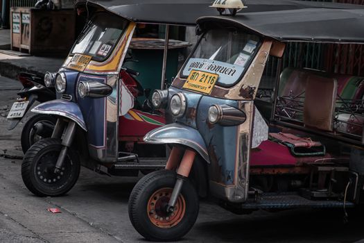 Famous blue Tuk Tuk or 3-wheeler taxi. Side of Two thai traditional taxi parked in an alley