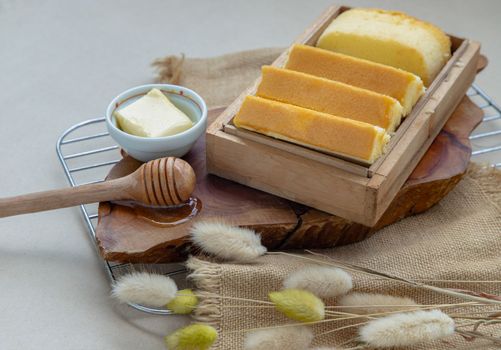 Slices of four butter cakes in wooden box served with butter and honey. 