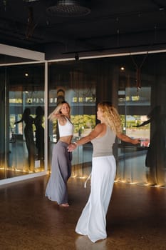 Two women in sportswear are doing dance yoga in the gym