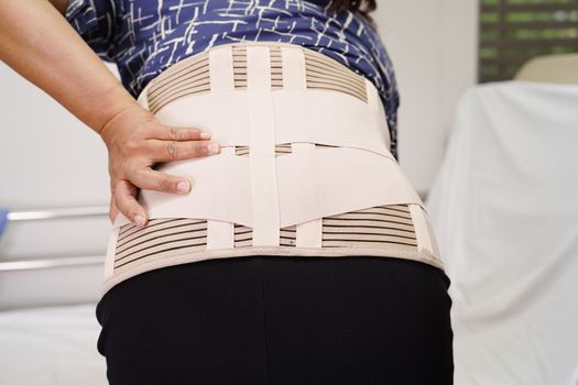Asian senior wearing elastic support belt can help reduce back pain.