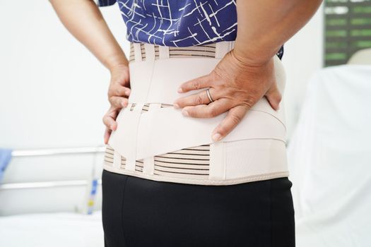 Asian senior wearing elastic support belt can help reduce back pain.