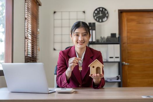Real estate woman holding house model and house key in hand.Mortgage loan approval home loan and insurance concept.