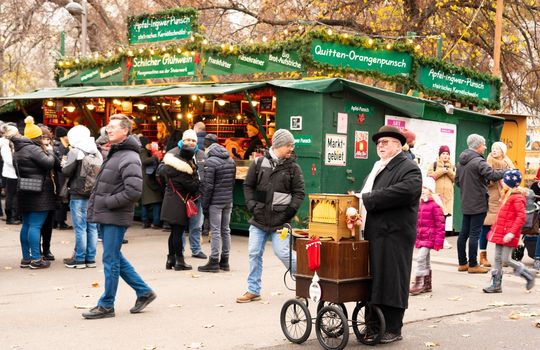 Vienna, Austria - December 10, 2022: Elderly organ grinder in the Christmas square