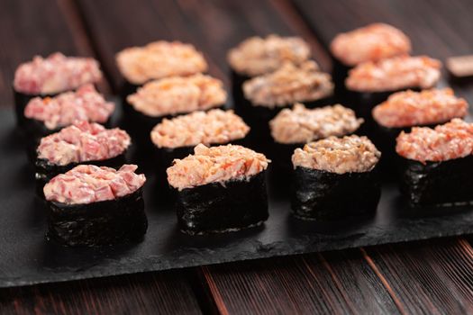Set of Gunkan Maki Sushi with different types of fish salmon, scallop, perch, eel, shrimp and caviar on wooden table background. Sushi menu. Japanese food sushi set gunkans