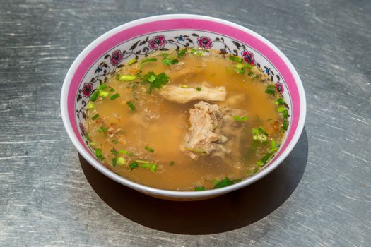 Hot clear soup of fresh pork rib seasoning with soy sauce and pepper. Pork bone soup in white bowl.