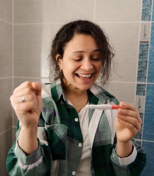 Charming woman rejoicing at positive pregnancy test. Finally pregnant. Close-up