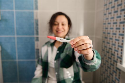 Positive pregnancy test in a happy woman's hands. People, maternity and pregnancy concept