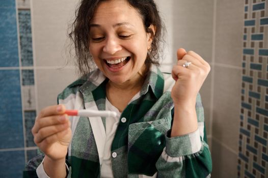 Charming middle-aged woman rejoicing at at positive pregnancy test