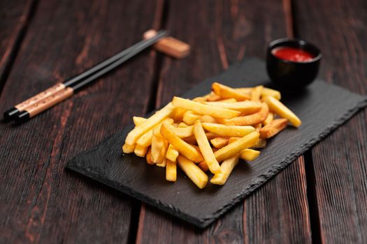French fries with ketchup on dark wooden background - fast food and unhealthy eat concept