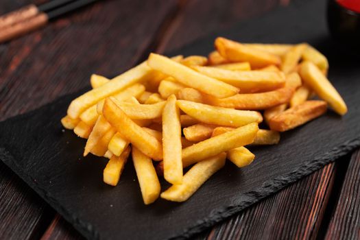 French fries on dark wooden background - fast food and unhealthy eat concept