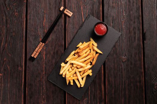 French fries with ketchup on dark wooden background top view - fast food and unhealthy eat concept