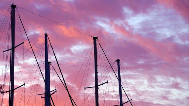 masts of a yacht without sails against the background of a sunset cloudy sky, copy space