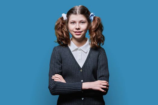 Portrait of smiling child schoolgirl on blue studio background