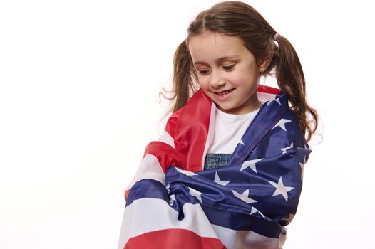Little girl American citizen wraps herself in USA flag, celebrates Independence Day- 4th July. Human rights and freedoms
