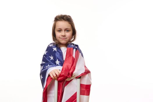 Isolated portrait on white background of a happy American little girl with USA flag and suitcase. Copy space for ad text