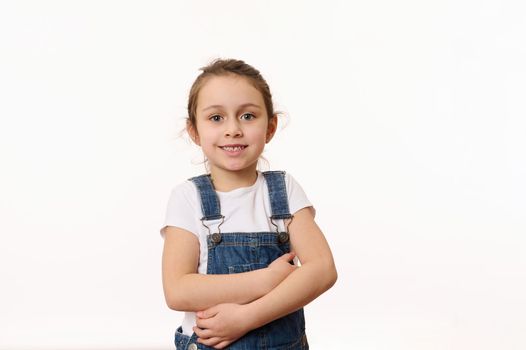 Emotional portrait of a cute baby girl, wearing blue denim overalls, isolated over white background with copy ad space