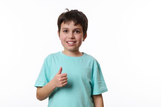 Emotional portrait of cute Caucasian teen boy, showing thumb up, smiling looking at camera, isolated on white background