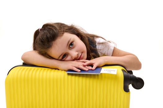 Lovely traveler baby girl with boarding pass and suitcase, traveling abroad for the weekend. Tourism. Air travel concept