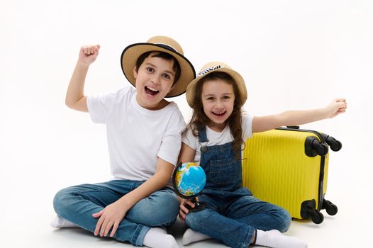 Cheerful young tourists travelers, boy and girl going abroad for weekend getaway, choosing destination on the globe map