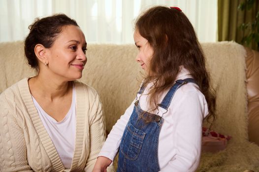 Beautiful multi-ethnic woman, a loving mother talking with her cute baby girl, looking at her with tenderness and love