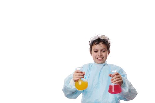 Young chemist - smart preteen schoolboy in laboratory coat, pouring chemical reagent in glass retort at chemistry class.