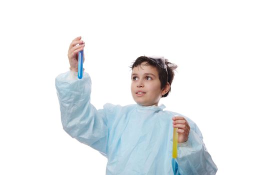Smart teenage boy, a young chemist scientist, lifting up a test tube with chemical liquid, isolated on white background