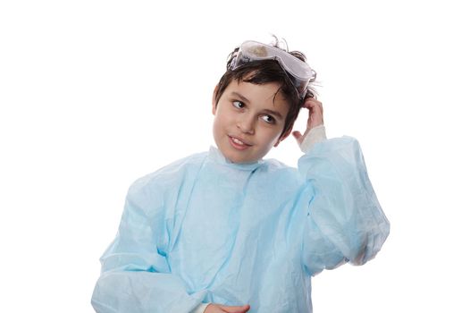 Isolated portrait on white background of a handsome schoolkid, adorable teenage boy in lab coat and safety goggles